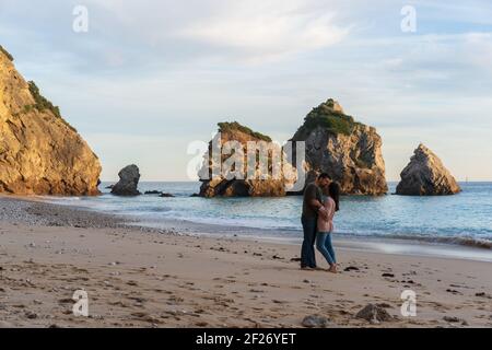 Couple embrassant sur une plage sauvage vide à Ribeiro do Cavalo, Arrabida, Portugal Banque D'Images