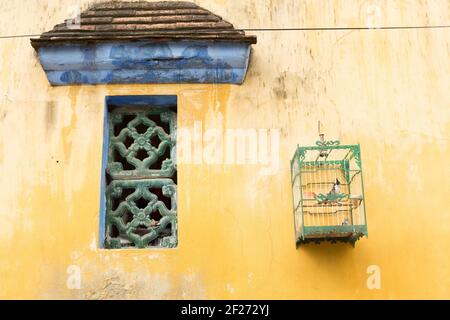 Vietnam, Ho Chi Minh ville - oiseau en cage suspendu à l'extérieur d'une maison coloniale traditionnelle. Banque D'Images