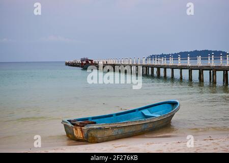 Bateau à ramer sur une plage de sable à côté d'un long quai sur l'île de Koh Rong Sanloem, Cambodge Banque D'Images