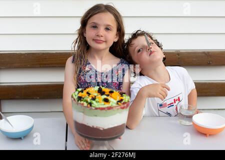 Frères et sœurs qui mangent du dessert dans leur arrière-cour Banque D'Images