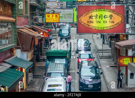 Île de Hong Kong, Chine - 14 mai 2010 : le trafic de voitures de rue commerçante montre beaucoup de panneaux d'affichage, un pour la boutique de médecine chinoise Beijing Tong Ren Tang, Banque D'Images