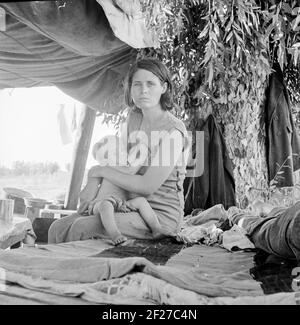 La photographie montre Zella (McCann) Power, épouse de Jess Power avec leur bébé Jesse Power. Réfugiés de la sécheresse du camping de l'Oklahoma au bord de la route. Ils espèrent travailler dans les champs de coton. Le responsable du service d'inspection à la frontière (Californie-Arizona) a déclaré que ce jour-là, le 17 août 1936, vingt-trois chargements de voitures et de camions de familles migrantes des comtés de sécheresse de l'Oklahoma et de l'Arkansas avaient traversé cette station entrant en Californie jusqu'à 3 heures dans l'après-midi . Août 1936. Photo de Dorothea Lange Banque D'Images