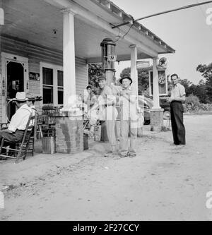 La station de remplissage rurale devient un centre communautaire et un terrain général pour le loafing. Les hommes en costume de baseball font partie d'une équipe locale qui jouera un match à proximité. L'équipe est appelée l'équipe de Cedargrove. Le 4 juillet, près de Chapel Hill, en Caroline du Nord. 4 juillet 1939. Photo de Dorothea Lange Banque D'Images