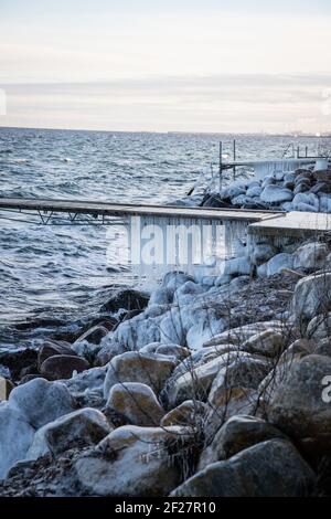 Les glaces pendent d'un pont gelé sur le bord de mer. Froid jour d'hiver. Banque D'Images