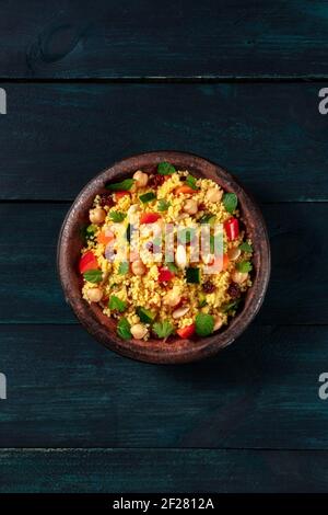 Salade de couscous végétarienne aux légumes et aux herbes, prise en hauteur sur fond de bois bleu foncé Banque D'Images