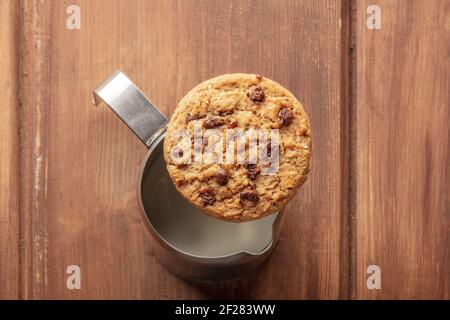 Bonjour. Un biscuit aux pépites de chocolat, tiré d'en haut sur un pot à lait, sur une table en bois rustique sombre Banque D'Images