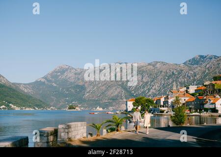 Un couple aimant marche en tenant les mains le long du remblai de La vieille ville de Perast Banque D'Images