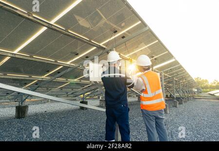 Un technicien avec un ingénieur vérifie les performances des panneaux solaires dans la centrale solaire, l'énergie alternative pour conserver l'énergie du monde, le photovol Banque D'Images