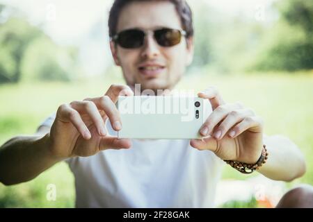Prendre des photos avec le téléphone portable : l'homme prend des photos avec son téléphone portable blanc Banque D'Images