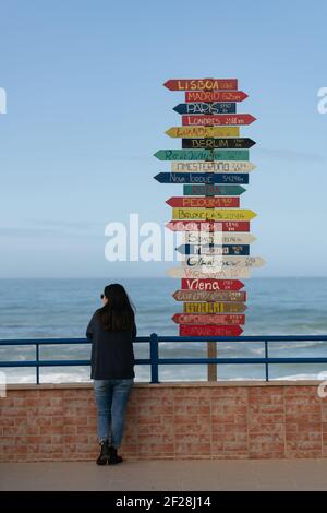 Femme voyageur près des flèches d'indication vers des villes du monde entier à Torres Vedras, Portugal Banque D'Images