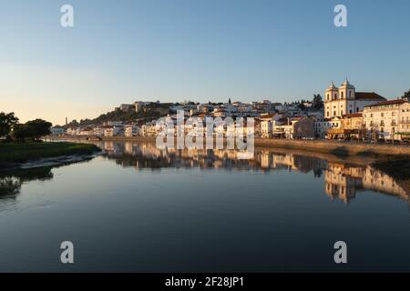 Vue sur le paysage urbain d'Alcacer do Sal depuis l'autre côté de la rivière Sado au coucher du soleil Banque D'Images