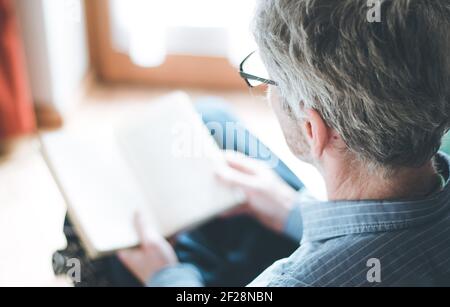 L'homme âgé est en train de lire un livre à la maison, foyer sélectif Banque D'Images