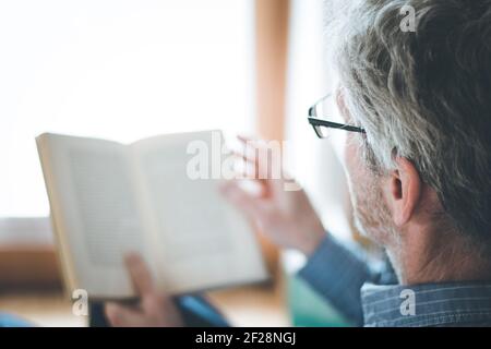 L'homme âgé est en train de lire un livre à la maison, foyer sélectif Banque D'Images