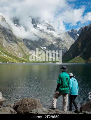 Un couple se tenant sur la rive du lac Marian et profitant de la vue, parc national Fiordland, Nouvelle-Zélande. Format vertical. Banque D'Images