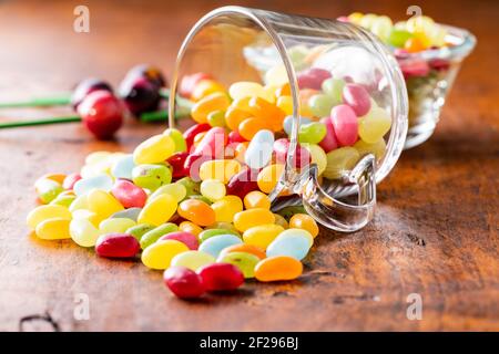 Haricots en gelée doux et colorés dans une tasse en verre sur une table en bois. Banque D'Images