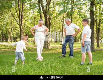 Bonne famille jouant au football sur la prairie estivale. Famille active Banque D'Images