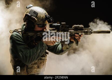 Soldat des forces spéciales visant avec son fusil dans le brouillard Banque D'Images