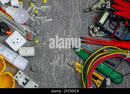 Outils électriques et un ensemble de composants à utiliser dans installations électriques sur fond gris avec un emplacement pour texte Banque D'Images