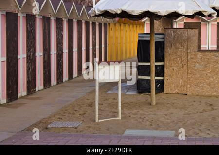 Petite panneau en bois sur le sable dans une salle de bains avec cabines de plage colorées en arrière-plan (Pesaro, Italie, Europe) Banque D'Images