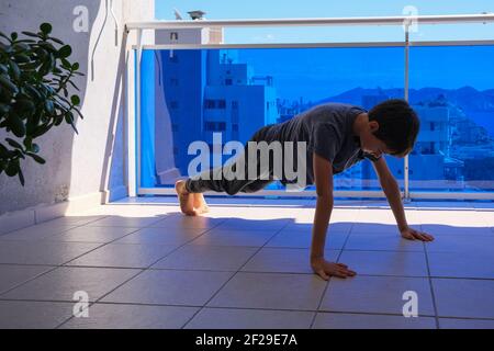 Enfants faisant des exercices de sport push-up sur le balcon. Sport, style de vie sain, entraînement, loisirs actifs à la maison Banque D'Images