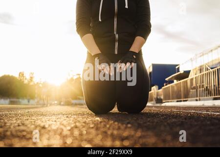 Fitness femme style de vie en noir tracksuit extérieur, blanc ciel ensoleillé fond. Lumière de coucher de soleil, mise au point sélective. Banque D'Images