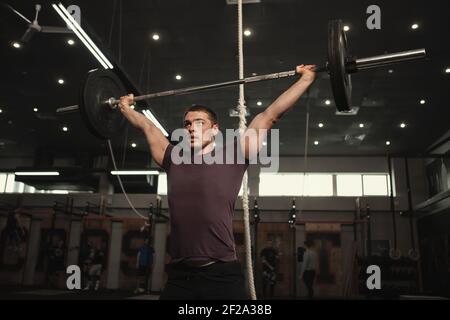 Photo basse d'un athlète de coupe transversale musclée soulever une lourde barbell au-dessus de la tête Banque D'Images