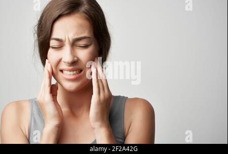 femme en t-shirt gris problèmes de santé tient la main près du visage douleur inconfort Banque D'Images