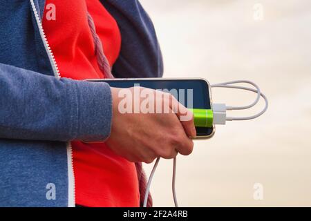Elle tient un smartphone et une batterie externe pendant la charge Banque D'Images