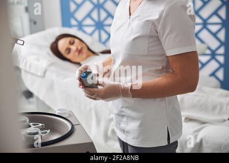 Femme médecin tenant un contenant en métal avec un tube à essai Banque D'Images