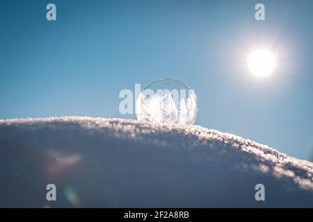 Bulle de savon surgelé avec un joli motif sur la neige gros plan sur un arrière-plan flou Banque D'Images