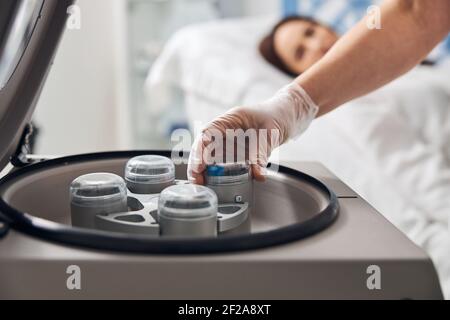 Mains de médecin féminin utilisant une centrifugeuse de laboratoire en clinique Banque D'Images