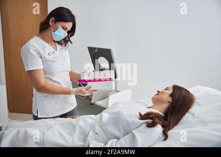 Femme médecin en masque médical parlant avec le patient en clinique Banque D'Images