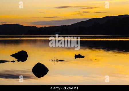 Coucher de soleil doré sur Coniston Water avec ciel orange reflété dans les eaux calmes en automne dans le parc national de Lake District. Coniston, Cumbria, Angleterre, Royaume-Uni Banque D'Images