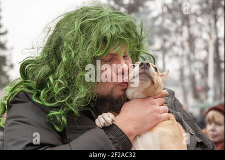 Kolomna, Russie, 17 mars 2013. Un homme dans une perruque verte embrasse son petit chien Jack Russell Terrier . Banque D'Images