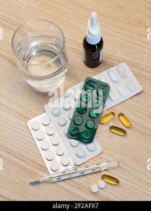 Thermomètre médical analogique pour vérifier la température avec des comprimés, capsules et pilules colorés sur la table. Vue de dessus vers le bas. Concepts médicaux et de santé. Banque D'Images