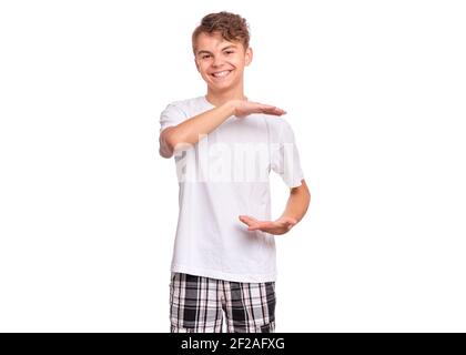 Beau garçon de l'adolescence montre quelque chose dans ses mains et regardant la caméra, isolé sur fond blanc Banque D'Images