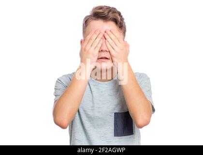 Beau garçon adolescent avec une expression triste couvrant le visage avec les mains en pleurant, isolé sur fond blanc Banque D'Images