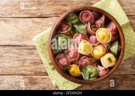 Les boulettes tortellini multicolores cuites se ferment dans un bol sur la table. Vue horizontale du dessus Banque D'Images