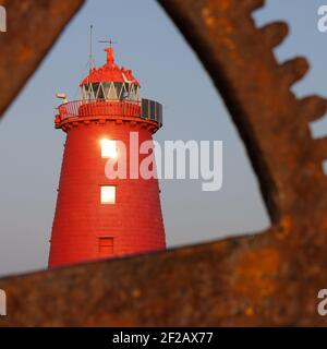 Poolbeg Lighthouse vu à travers l'équipement et la grue de port, phare rouge, port de Dublin, équipement rouillé, ancienne grue manuelle, ciel bleu, carré, Banque D'Images