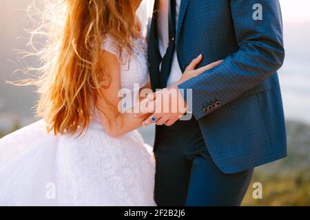 La mariée et le marié se tiennent sur un rocher à l'intérieur les montagnes et de tenir les mains Banque D'Images