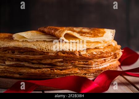 Une pile de crêpes fines sur un fond en bois sombre de gros plan. Un plat traditionnel de crêpes pour les vacances Maslenitsa. Place pour votre texte, photo pour Banque D'Images