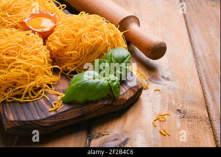 Les pâtes tagliatelles sont minces. Traditionnel italien appelé Angel Hair. Pâtes italiennes aux œufs, faites maison et fraîches sur une table en bois. Cuisine rustique du nord de l'Italie. Copier l'espace Banque D'Images