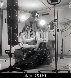 photographe et mannequin de mode des années 1940. Une jeune femme modèle est dans un studio de photographes reçoit quelques instructions finales avant de prendre les photos. Les lampes et la caméra sont visibles. Suède 1949 réf. AT7-7 Banque D'Images