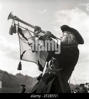 Événement historique recréé. Un homme vêtu d'un uniforme historique souffle à travers une trompette fanfare. Un ancien avertisseur sonore en laiton sans vannes qui ne pouvait produire que des tonalités faites par le trompettiste. Un drapeau avec un symbole est suspendu de la trompette. Suède 1944 réf. H92-5 Banque D'Images