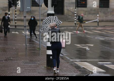 Amsterdam, pays-Bas. 11 mars 2021. Une femme tente de tenir son parapluie pendant la tempête le 11 mars 2021 à Amsterdam, pays-Bas. L'Institut néerlandais de météorologie KNMI a émis un avertissement météorologique jaune pour le pays avec des vents forts et des rafales jusqu'à des vitesses de vents allant jusqu'à 80 à 100 km par heure. (Photo de Paulo Amorim/Sipa USA) Credit: SIPA USA/Alay Live News Banque D'Images