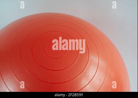Photo détaillée d'un bord-côte circulaire sur un ballon de gym gonflable rouge sur fond blanc. Banque D'Images