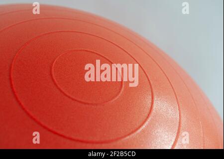Gros plan photo de côtes circulaires sur un ballon de gym gonflable rouge sur fond blanc. Banque D'Images
