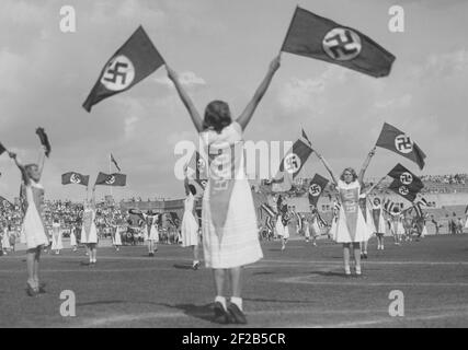 L'Allemagne dans les années 1930. Les écoliers allemands pratiquent une routine sur Berlins sportsarena Deutsches Stadion. L'utilisation du drapeau national socialiste fait partie de la routine. Le drapeau est devenu le drapeau allemand nazi seulement officiel à partir de 1935. Banque D'Images