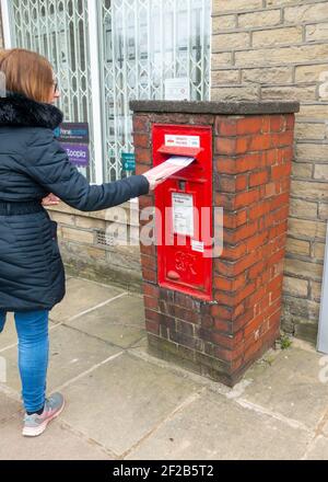 Boîte postale en briques rouges sur pied, boîte postale avec une femme affichant une lettre, à Shelf, Halifax, West Yorkshire, Royaume-Uni Banque D'Images