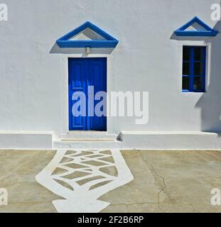 Église orthodoxe grecque traditionnelle façade blanchie à la chaux avec porte en bois bleu, fenêtre et fronton sur l'île de Karpathos, en Grèce dodécanèse. Banque D'Images